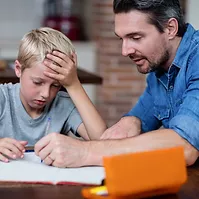 Père aidant son enfant pour les devoirs scolaires